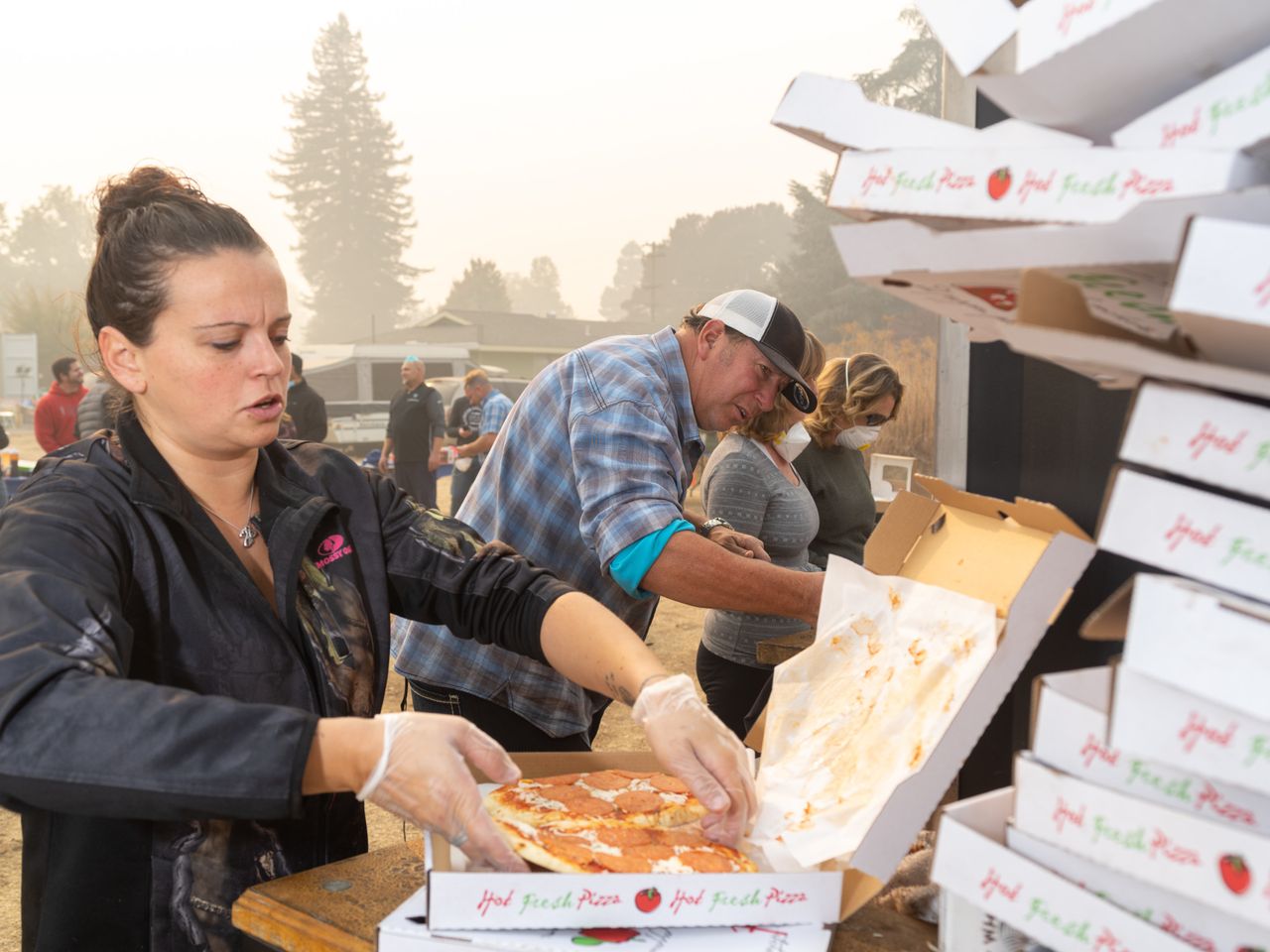 Rolling Stone mobile pizza chef Jim King works with other volunteers to distribute pizzas at the East Ave Church shelter.