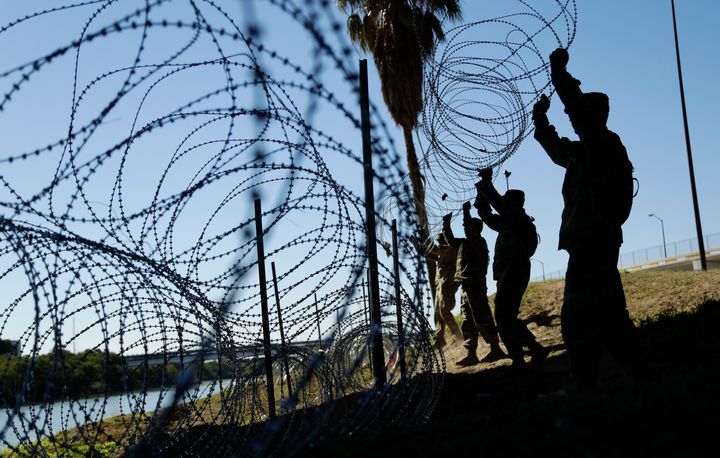 Members of the U.S. military install multiple tiers of concertina wire along the banks of the Rio Grande near the Juarez-Linc