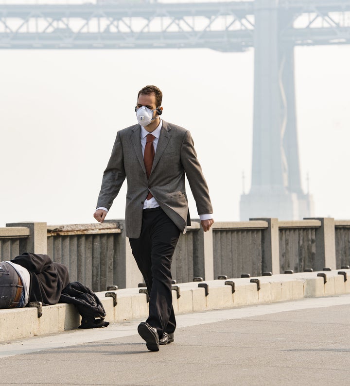 A man wearing a mask walks past a sleeping homeless person on Nov. 15 in San Francisco.