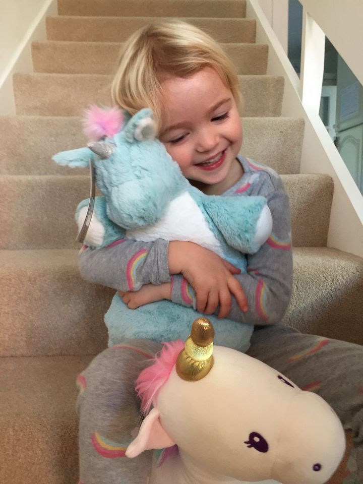 Margo hugs her favourite unicorn toy.