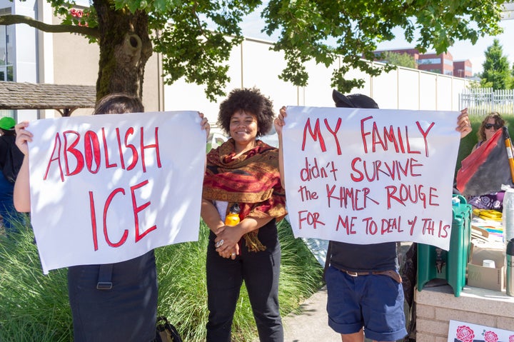 Protesters hold up signs demanding the abolition of ICE and recalling the ordeal of refugees under the Khmer Rouge regime in