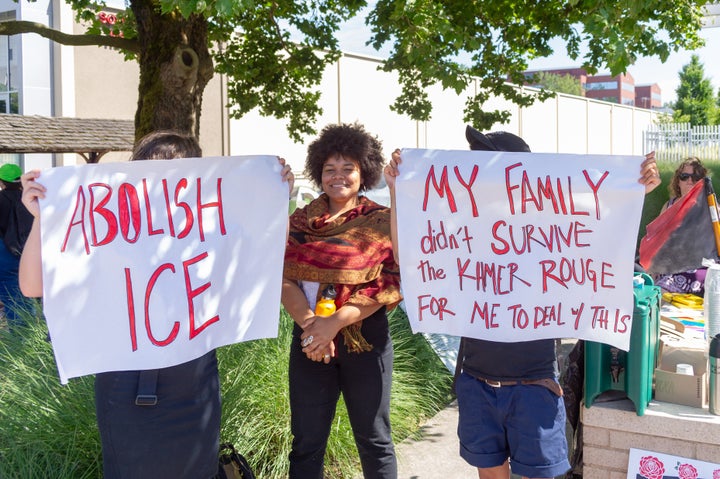 Protesters hold up signs demanding the abolition of ICE and recalling the ordeal of refugees under the Khmer Rouge regime in Cambodia.