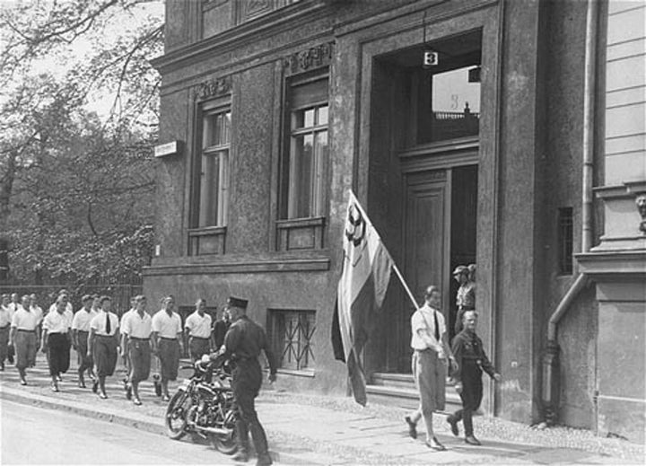 Students organized by the Nazi party parade in front of the building of the Institute for Sexual Research in Berlin prior to pillaging it on May 6, 1933. United States Holocaust Memorial Museum