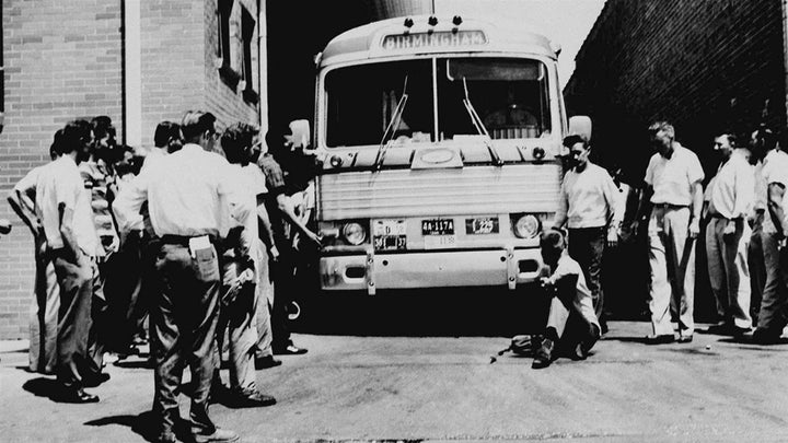 An unidentified white man sits in front of a Greyhound bus to prevent it from leaving the station with a load of Freedom Riders in Anniston, Alabama, in 1961. The Anniston bus station is being restored with state and federal money. 