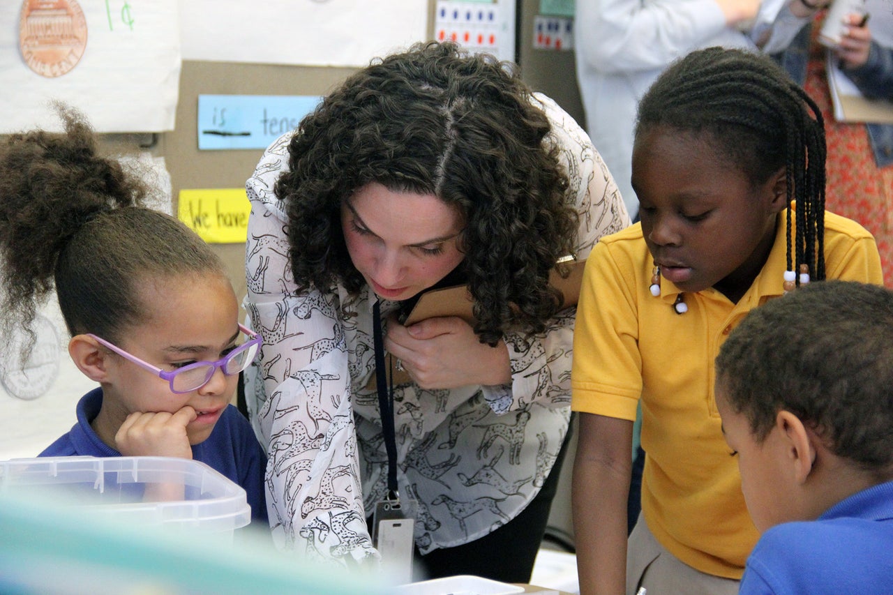 Sasha Redlener, a first-grade teacher at Mott Haven Academy Charter School, helps her students with an assignment. Classes at the school mix “body breaks” and other playtime with reading and math instruction and lessons in social and emotional skills. 