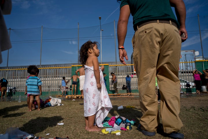 A girl traveling with the migrant caravan talks with her father after taking a bath Wednesday at a shelter in Tijuana, M