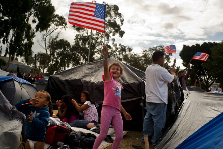 Seven-year-old Honduran migrant Genesis Belen Mejia Flores waves an American flag at two U.S. border control helicopters flyi