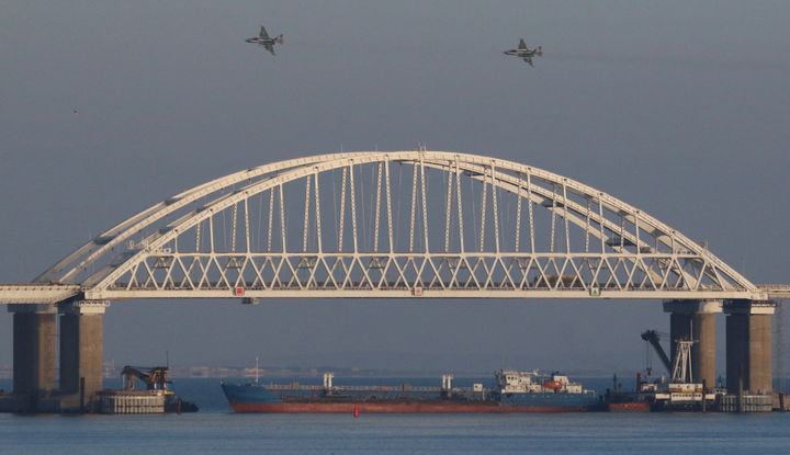 Russian jet fighters fly over a bridge connecting the Russian mainland with the Crimean Peninsula with a cargo ship beneath it after three Ukrainian navy vessels were stopped by Russia from entering the Sea of Azov via the Kerch Strait in the Black Sea.