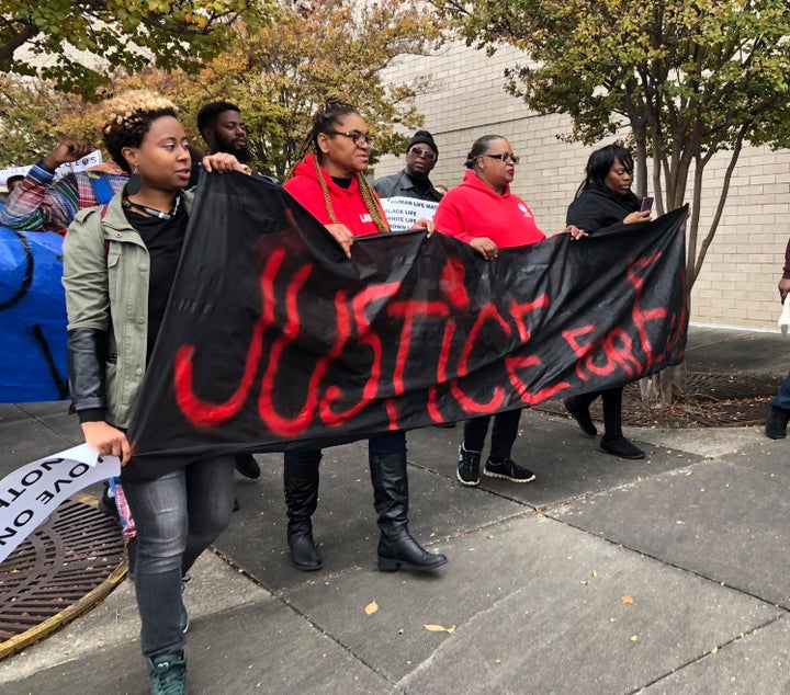Protestors carry a sign reading “Justice for E.J.” during a protest at the Riverchase Galleria in Hoover, Alabama