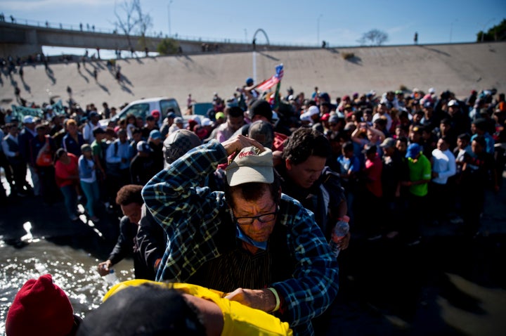 Migrants cross the river at the Mexico-U.S. border on Sunday after pushing past a line of Mexican police at the Chaparral cro