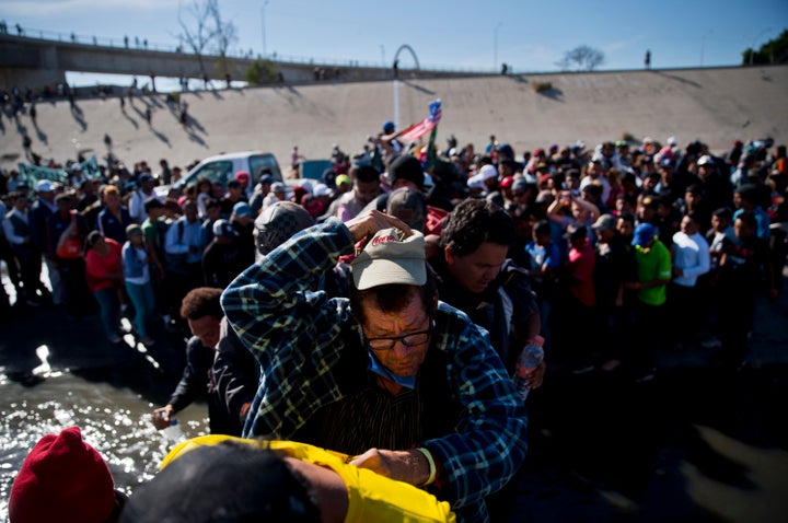 Migrants cross the river at the Mexico-U.S. border on Sunday after pushing past a line of Mexican police at the Chaparral crossing in Tijuana, Mexico.