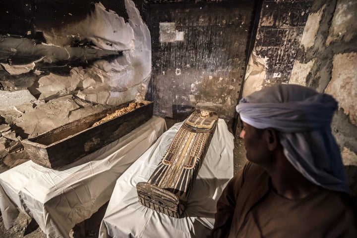 An Egyptian worker standing next to an opened intact sarcophagus containing a well-preserved mummy of a woman named "Thuya" w