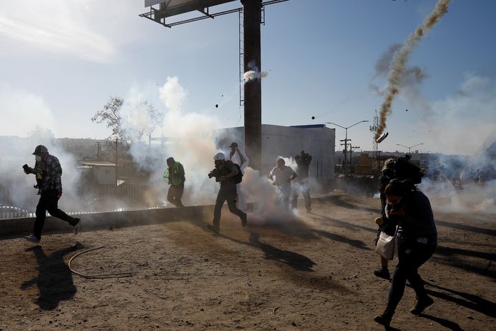 Migrants, part of a caravan of thousands traveling from Central America en route to the United States, and journalists flee tear gas released by U.S. border patrol near the fence between Mexico and the United States in Tijuana, Mexico, Nov. 25, 2018. 