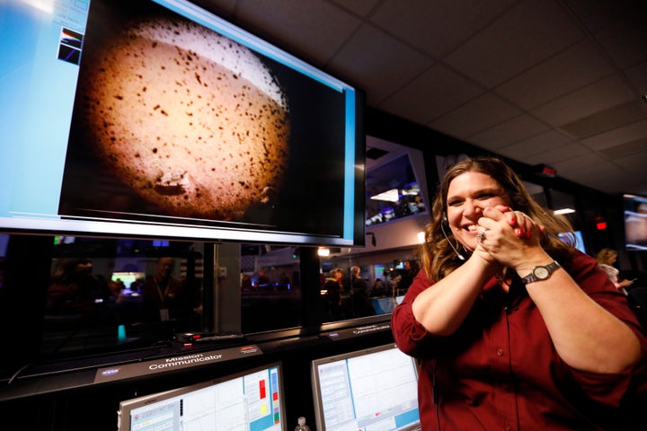 An engineer smiles next to an image of Mars sent from the InSight lander shortly after it landed on Mars.