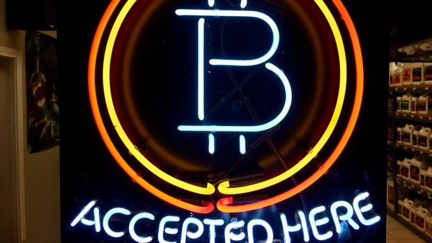 FILE - In this Feb. 7, 2018 file photo, a neon sign hanging in the window of Healthy Harvest Indoor Gardening in Hillsboro, Ore., shows that the business accepts bitcoin as payment. A raft of recent cyber-security firms and governments now cite the rising trend of ‘crypto-jacking’ _ in which devices are infected with invisible malicious cryptocurrency mining software that uses the computing power of victims’ devices to mine virtual currency _ as the main cyber security threat to businesses and consumers worldwide. (AP Photo/Gillian Flaccus, File)