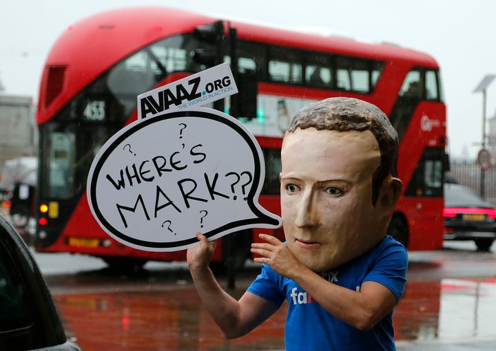 An activist wearing a Mark Zuckerburg mask stands outside the UK Parliament in Westminster.