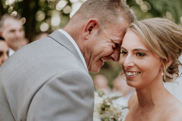 A close-up of the bride and groom's smiling faces, their foreheads touching. The groom is in profile, with the bride angled toward the camera.