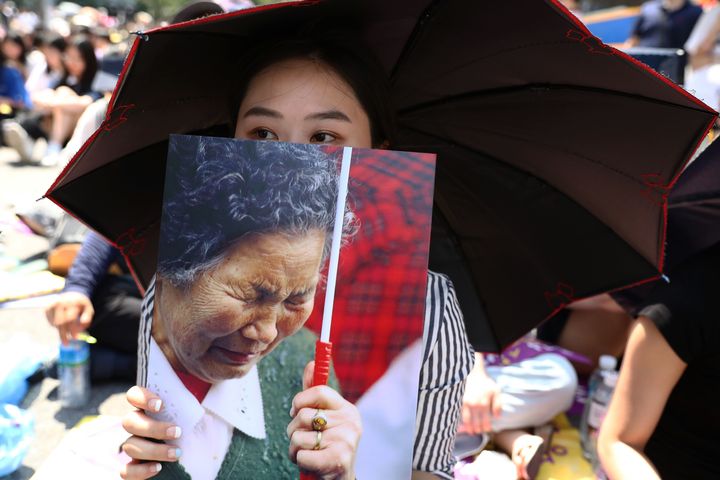 Γυναίκα στη Νότια Κορέα μετέχει στους εορτασμούς για την 73η επέτειο από την απελευθέρωση της χώρας από την Ιαπωνία κρατώντας τη φωτογραφία μιας εκ των χιλιάδων «γυναικών ανακούφισης» που χρησιμοποιούνταν ως σκλάβες του σεξ, στην υπηρεσία των Ιαπώνων στρατιωτών.
