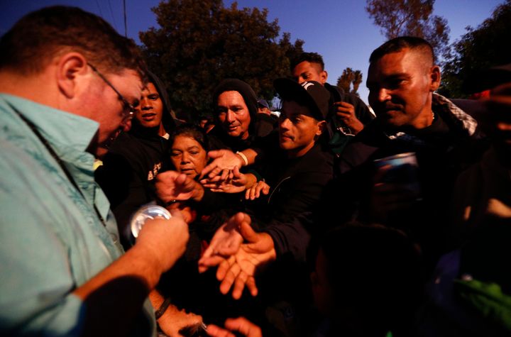 An American well-wisher, left, is swarmed by migrants as he hands out canned soup, adding his efforts to those of many local Mexican groups distributing food outside of a sports complex where more than 5,000 Central Americans are sheltering in Tijuana, Mexico.