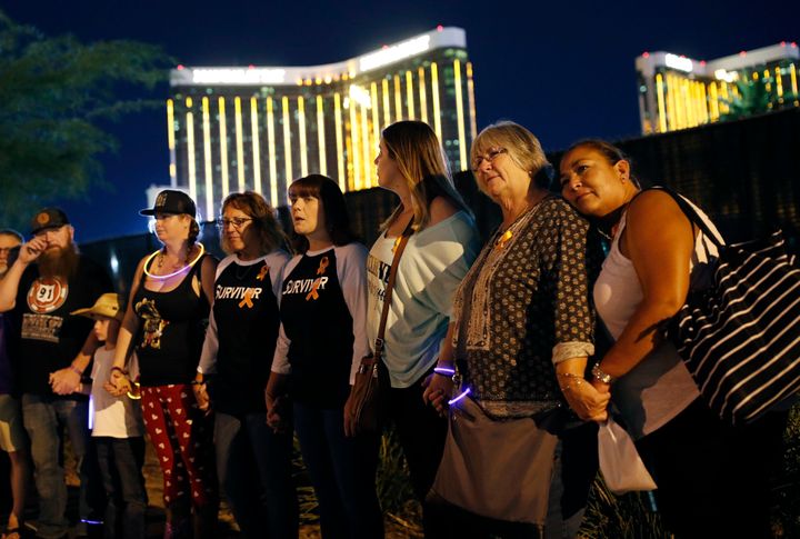 Survivors of the Oct. 1, 2017, mass shooting in Las Vegas form a chain around the shuttered site of a country music festival on the first anniversary of the shooting. The Justice Department has awarded more than $16 million to the victims.