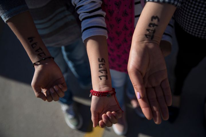 Lorena and her two children hold out their arms to show the numbers they were given to be on a list at Casa Del Migrante to seek political asylum in the United States on November 28, 2018. (Photo: Adria Malcolm for Yahoo News)
