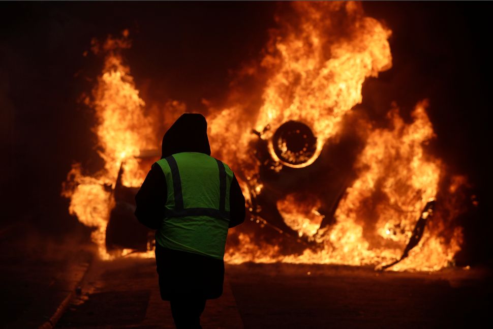 A demonstrator watches a burning car near the Champs-Elysees avenue.