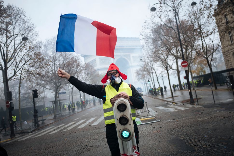 A demonstrator holds a French flag near the Arc de Triomphe.