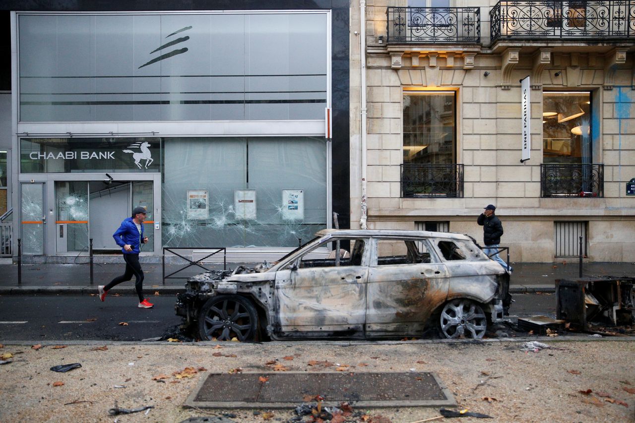 A Parisian runs beside a burnt-out car on Sunday.