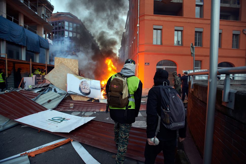 Rioters stand near flames and a barricade on Saturday.