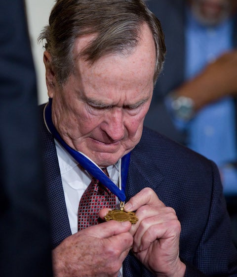 <p>The late President Bush reads the inscription on the 2010 Presidential Medal of Freedom he was awarded by former President Obama. </p>