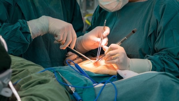 A cosmetic surgeon operates on a patient