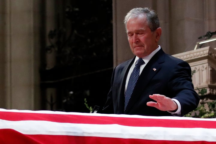 Bush touches his father's casket during the funeral ceremony. He praised him as "the best father a son or daughter could