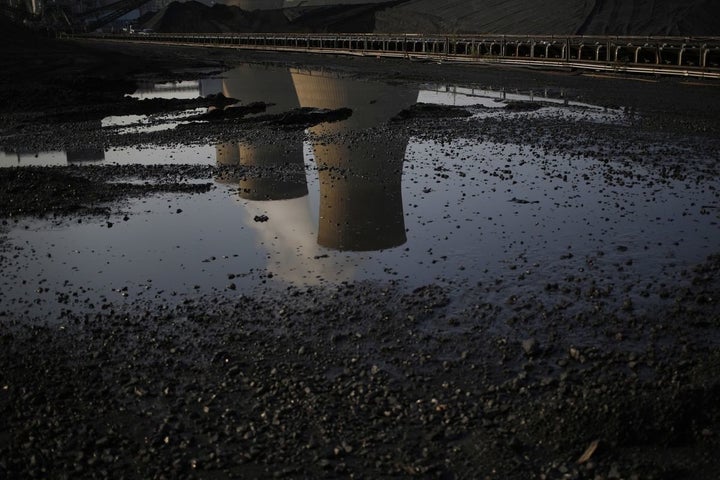 Cooling towers are reflected in a puddle at the American Electric Power Company's coal-fired John E. Amos Power Plant in Winfield, West Virginia.