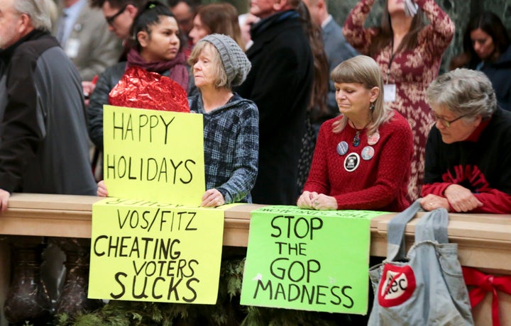 Protesters Peppi Elder, left, and Christine Taylor holds up signs during the state Christmas Tree lighting ceremony in state 