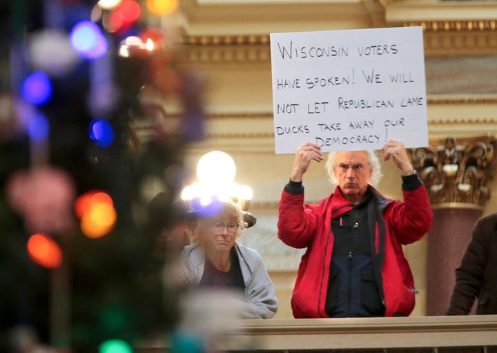 A protestor holds a sign as Wisconsin Republicans strip the incoming Democratic governor of power during the 2018 lame duck session.