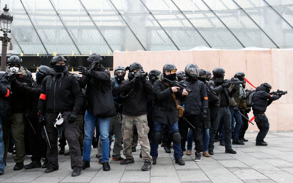 Police officers stand prepared to fire teargas at demonstrators.