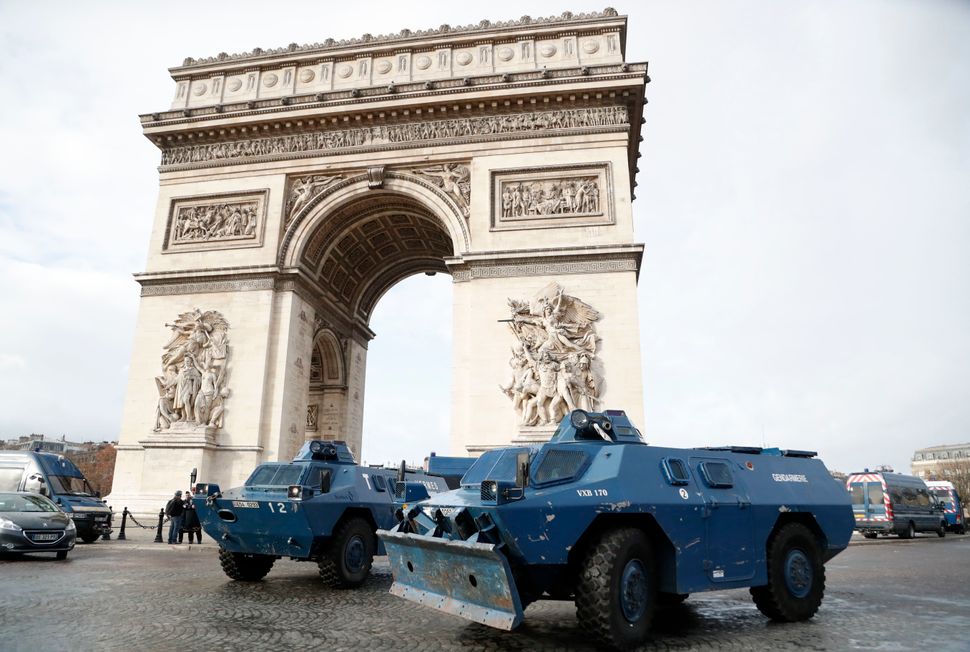 Police armoured personnel carriers are parked in front of the Arc de Triomphe.