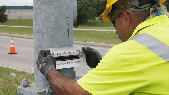 David Tubb puts a sticker on the base of a streetlight in Tulsa, Oklahoma, where new aluminum wiring was installed last year.