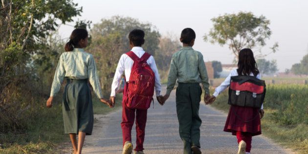 India, Uttar Pradesh, Agra, four young children walking to school hand in hand, back to camera.