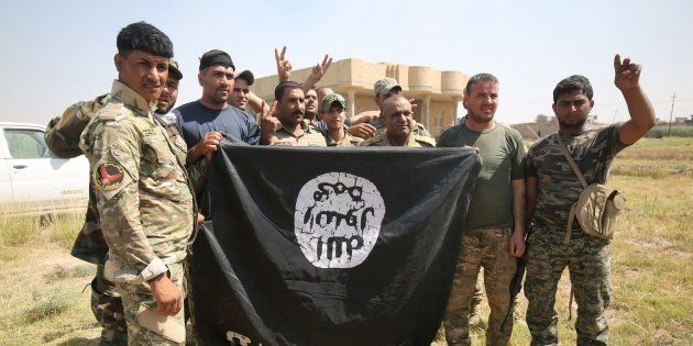 Iraqi Shiite fighters from a Popular Mobilisation unit hold an Islamic State (IS) group flag in an operation in al-Shahabi village, east of Fallujah, to retake the city from (IS) jihadists, on May 24, 2016.Iraqi forces cleared areas around Fallujah on May 24 after launching an assault to retake the city, tightening their siege on Islamic State group fighters. With the jihadists surrounded and outnumbered, the recapture of their iconic bastion looked ultimately inevitable, especially after IS suffered a string of losses in recent months. / AFP / AHMAD AL-RUBAYE (Photo credit should read AHMAD AL-RUBAYE/AFP/Getty Images)