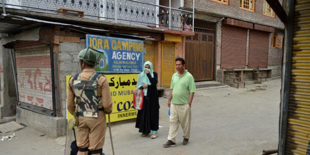 An Indian paramilitary trooper stops a Kashmiri couple during a curfew in Srinagar on July 12, 2016.