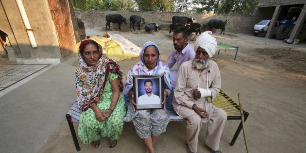 Malkit Kaur, mother of Kuldeep Singh, a cotton farmer who committed suicide, holds his portrait as Kuldeep's father Thana Singh (R), his brother Hardeep Singh (2nd R) and his widow Bhinder Kaur (L) sit on a cot at their residence on the outskirts of Bhatinda in Punjab, India, October 28, 2015.
