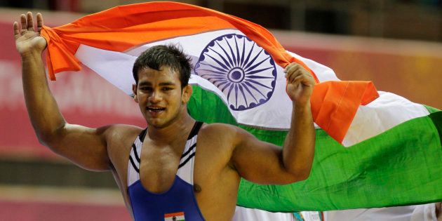 India's Narsingh Pancham Yadav holds his national flag as he celebrates winning the gold medal in the 74kg men's freestyle wrestling match at the Commonwealth Games in New Delhi October 9, 2010. REUTERS/Krishnendu Halder (INDIA - Tags: SPORT WRESTLING)