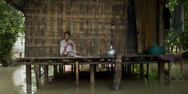 An Indian Mishing tribal woman sits at her traditional hut surrounded by flood waters at Majuli.