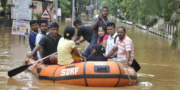 Indian residents navigate floodwaters in the Anilnagar area of Guwahati on July 7, 2016.