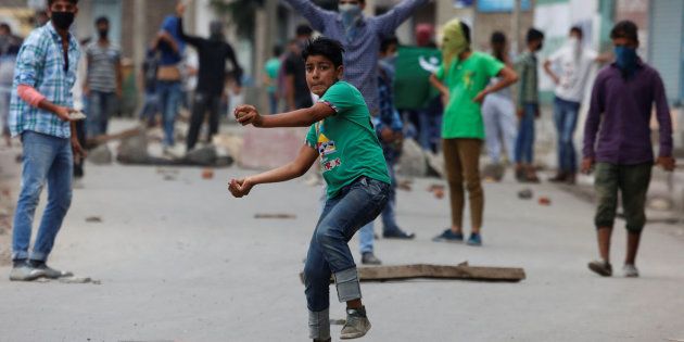 A protester throws stones towards the Indian police during a protest in Srinagar.