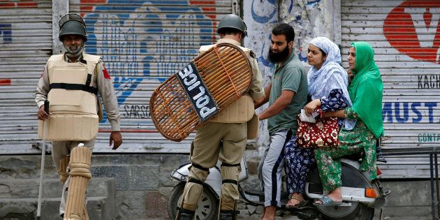 An Indian policeman checks the identification cards of a family during a curfew in Srinagar, August 8, 2016.