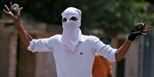 A masked protester gestures towards the Indian police during a protest in Srinagar, against the recent killings in Kashmir, India August 4, 2016.
