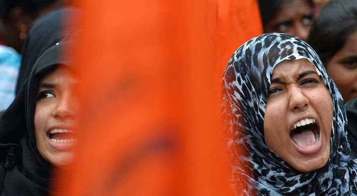 Muslim students and activists of the Akhila Bharatiya Vidyarthi Parishad (ABVP) hold saffron flags as they raise slogans against anti-national forces during a protest in Bangalore on August 17, 2016.