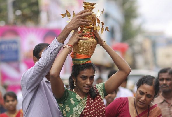 Indian badminton player P V Sindhu carries on her head decorated pots filled with cooked rice as an offering for Hindu goddess Kali as she performs a ritual during the festival of 'Bonalu' at a temple in Hyderabad, India, Sunday, July 31, 2016. (AP Photo/Mahesh Kumar A.)